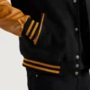 Men’s black varsity letterman jacket with wool body and gold leather sleeves closup view