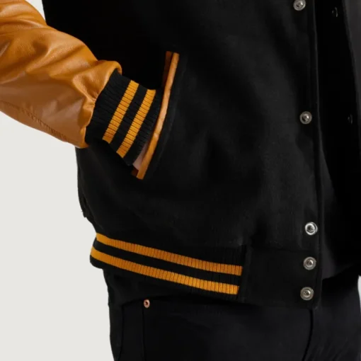 Men’s black varsity letterman jacket with wool body and gold leather sleeves closup view